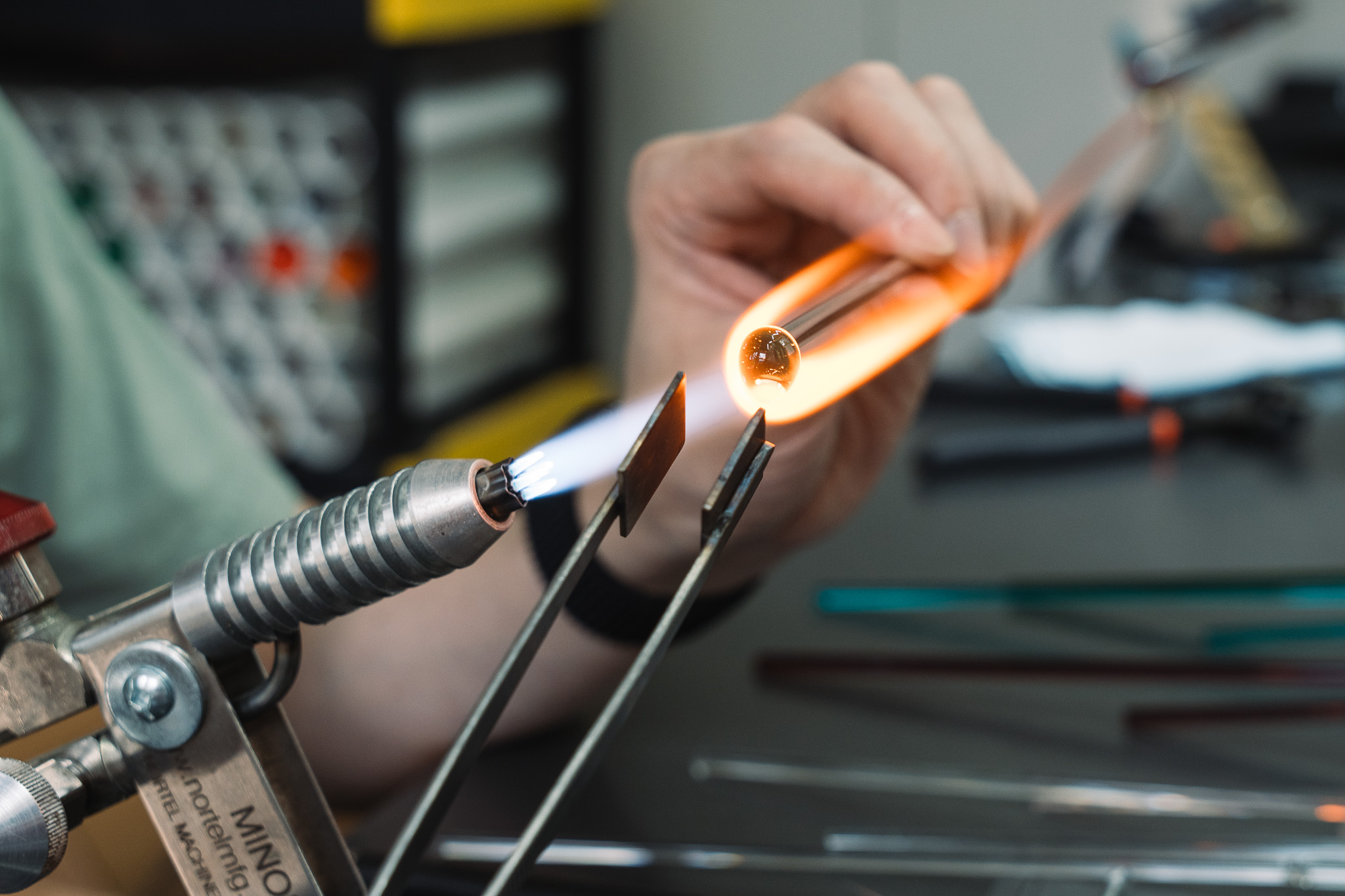 A glowing gather of glass being flattened with graphite tools.