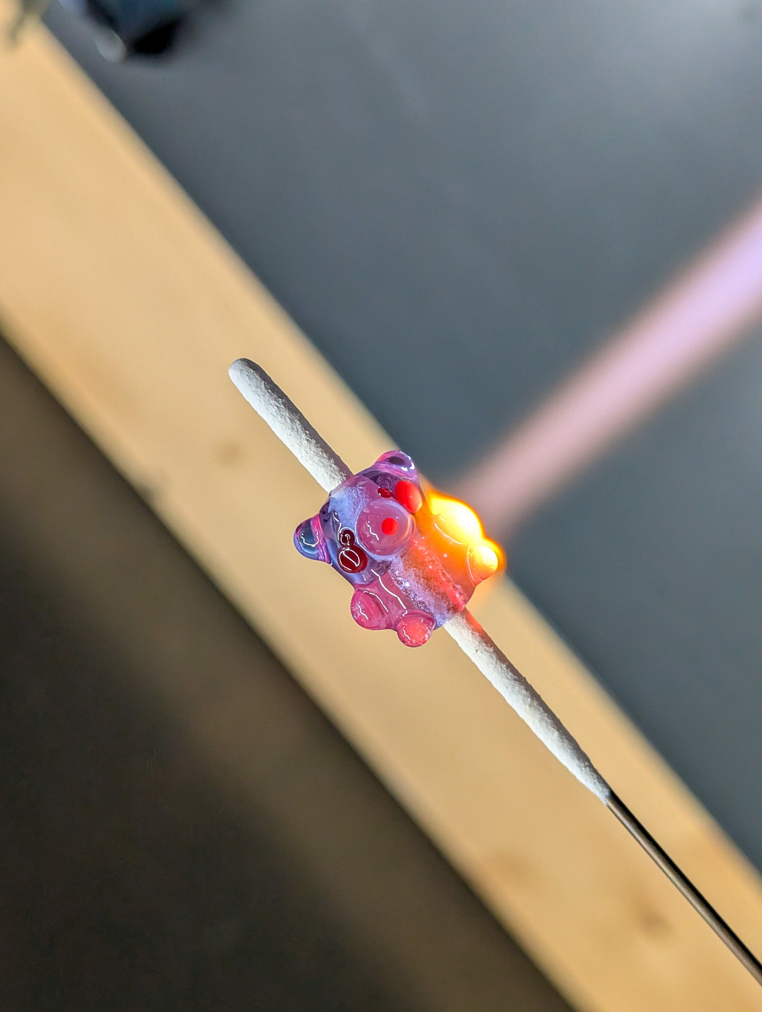 A small purple glass bear being warmed in the torch flame.