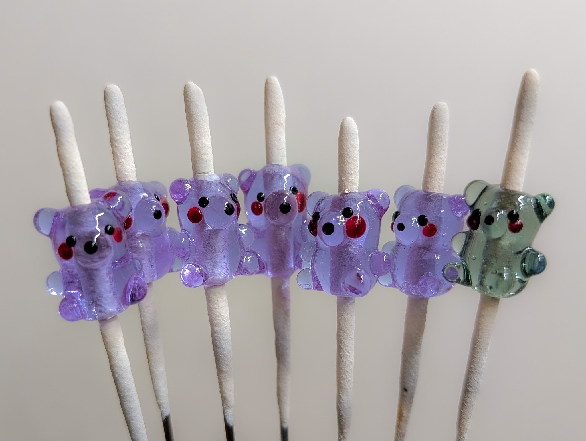 Rows of small purple glass bear beads on mandrels