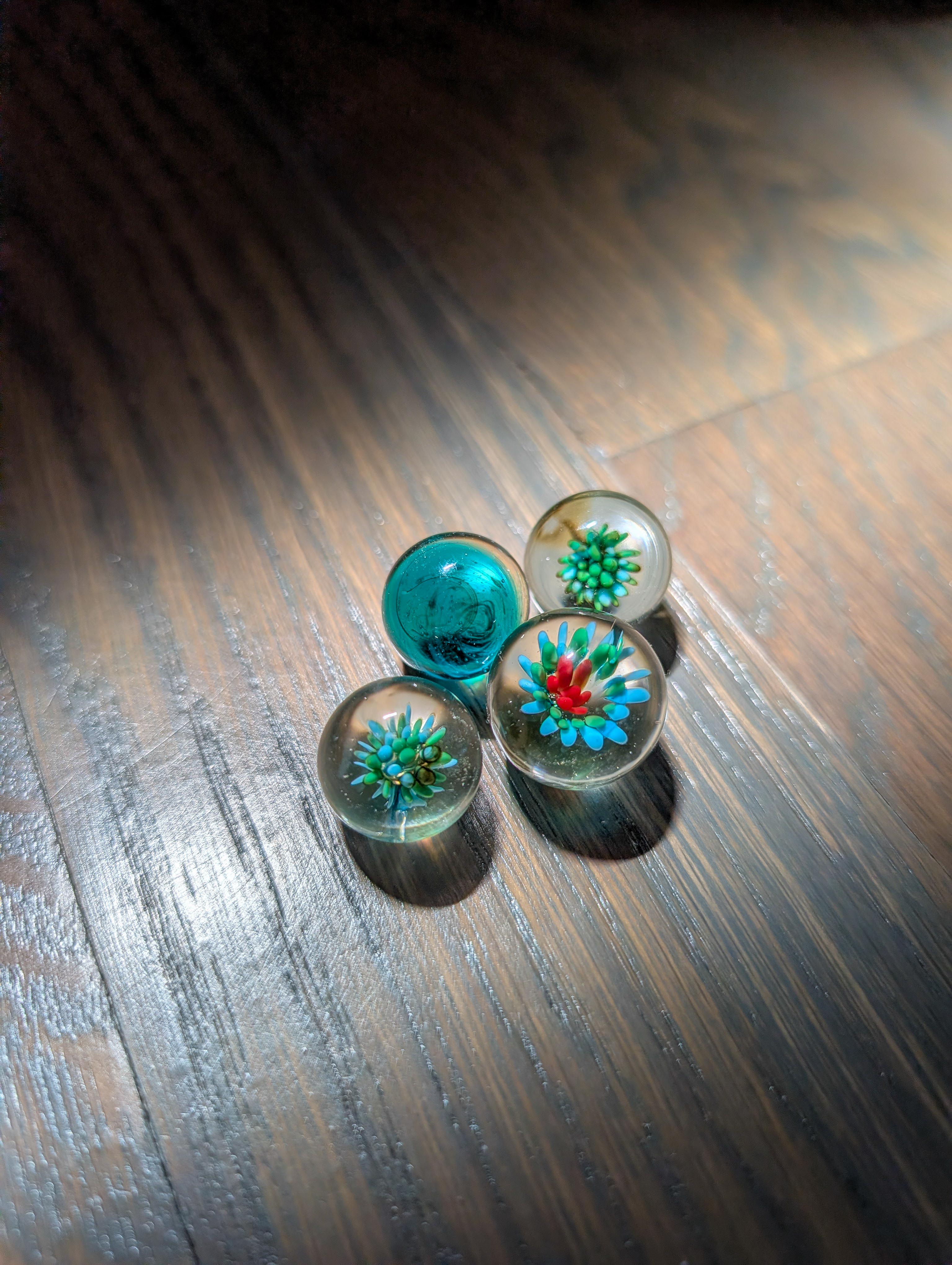 Four handmade glass marbles on dark wood